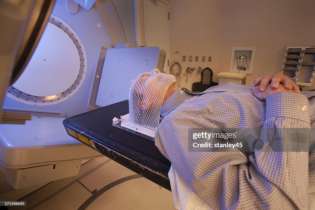 Male patient lying down with a radiation therapy mask