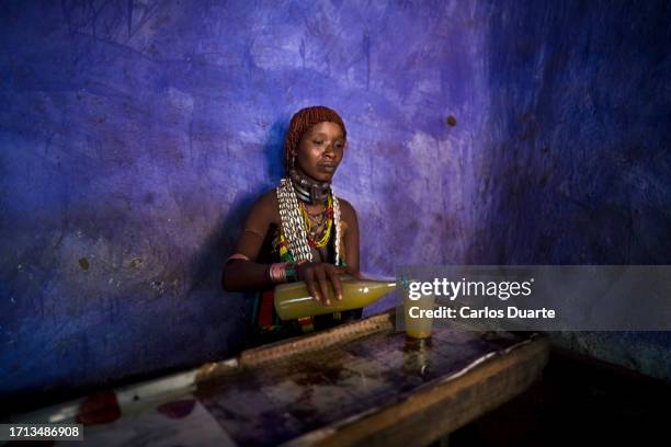 a hamer woman enjoys the typical hamer drink made of honey and alcohol inside a bar in dimeca in the omo valley, ethiopia. - ethiopië stockfoto's en -beelden