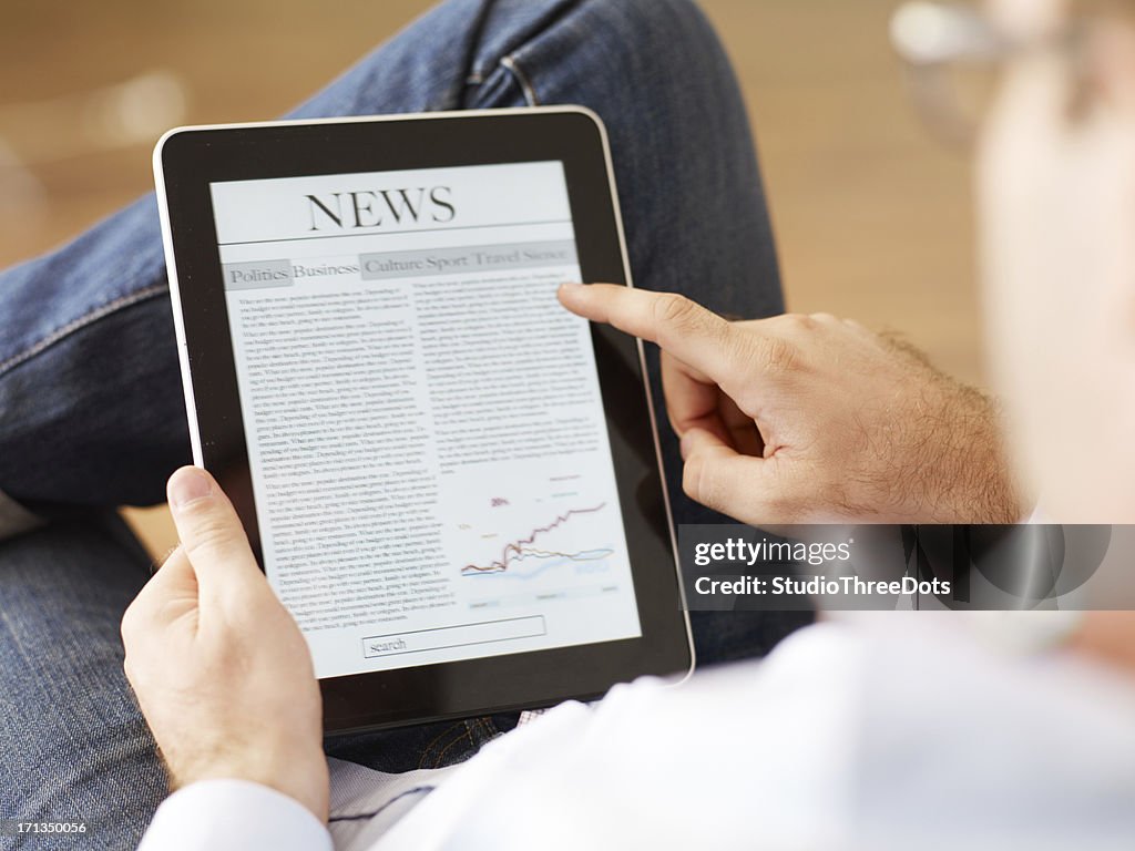 Man reading the newspaper on digital tablet