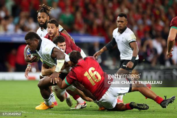 Fiji's inside centre Josua Tuisova is tackled by Portugal's inside centre Jose Lima Portugal's wing Raffaele Storti and Portugal's hooker David Costa...