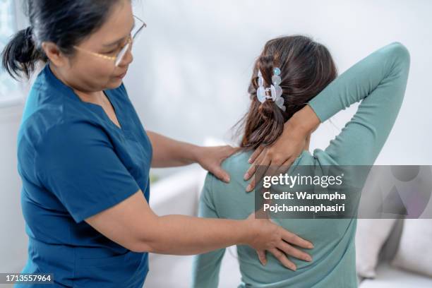 physical therapist massages a patient's back to treat and reduce pain. - neck stock pictures, royalty-free photos & images