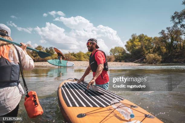 happy couple doing water sports with the stand up paddle - paddleboarding team stock pictures, royalty-free photos & images