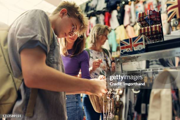 family browsing souvenirs in small souvenir shop in london, united kingdom - teenager boy shopping stock pictures, royalty-free photos & images