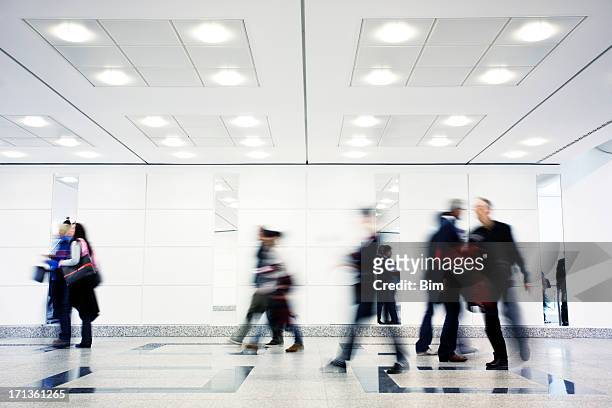 group of motion blurred people walking through illuminated corridor - ceiling light stockfoto's en -beelden