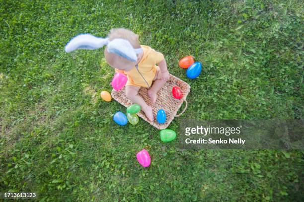 easter tradition of searching eggs in grass. children easter egg hunters with baskets and hare ears. - baby bunny stock pictures, royalty-free photos & images