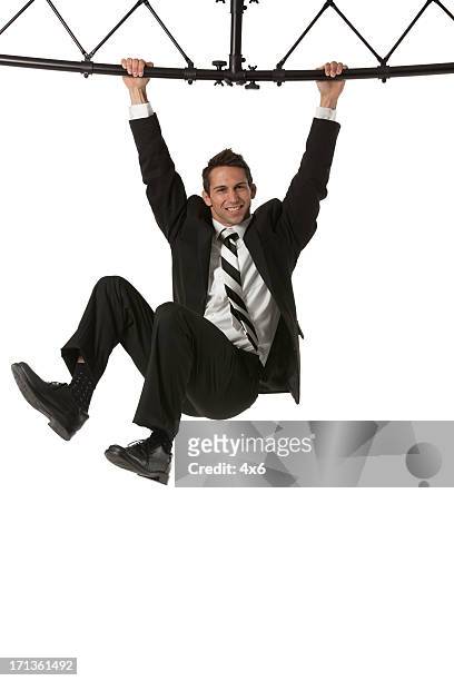 businessman hanging from a metal structure - suits hanging stock pictures, royalty-free photos & images
