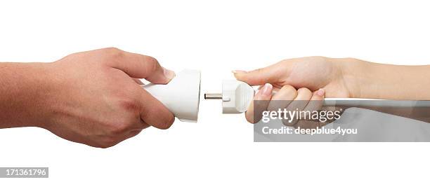 man and woman hands holding european plug and outlet isolated - hand plugging in stock pictures, royalty-free photos & images