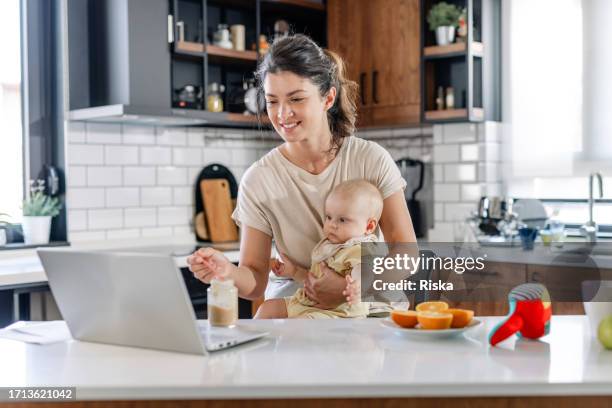 supermom mode: feeding and working at home - onschuld stockfoto's en -beelden