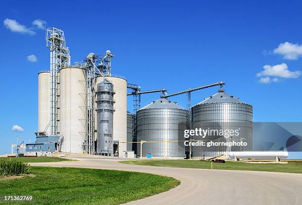 long shot of grain elevator facility on a sunny day - silos stock pictures, royalty-free photos & images