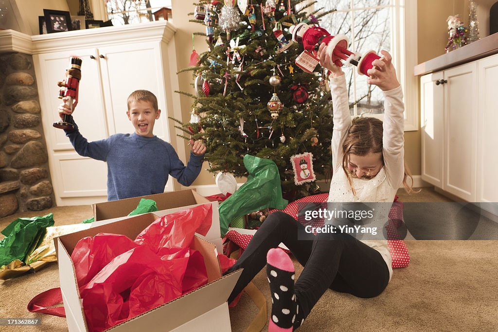 Happy Excited Children Opening Christmas Gifts in Front of Tree