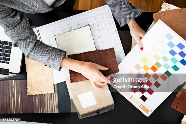 woman picking out swatches from desk - design professional stockfoto's en -beelden
