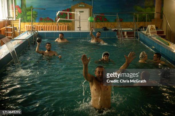 Soldiers and civilians swim in a pool at a rehabilitation center working with soldiers suffering from injuries and psychological trauma on October...
