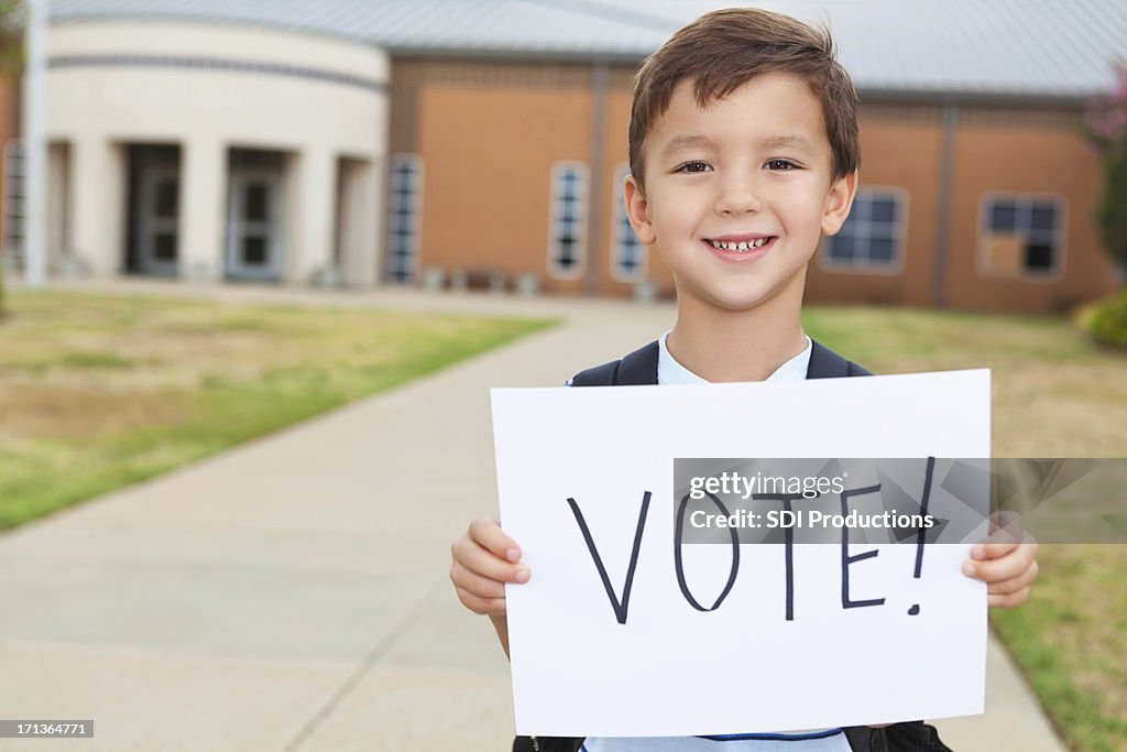 Happy young student at school holding a Vote Sign