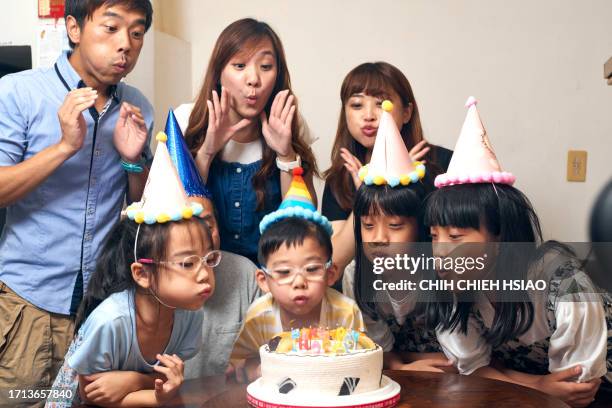 un bambino di 5 anni spegne le candeline alla sua festa di compleanno. - older mother baby 40 years foto e immagini stock