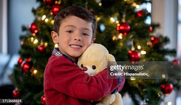 クリスマスを祝い、新しいテディベアを抱きしめる幸せな男の子 - traditional teddy bears prepared ahead of festive season ストックフォトと画像