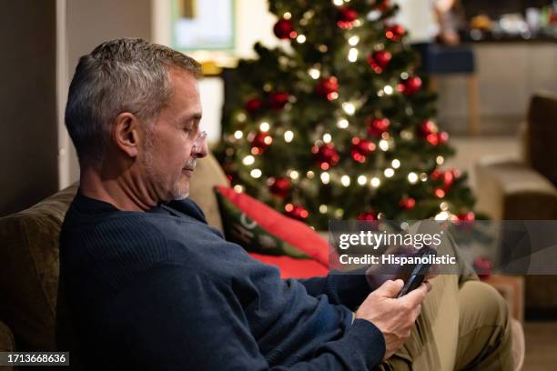 mature man texting on his cell phone on christmas eve - chat noel stockfoto's en -beelden