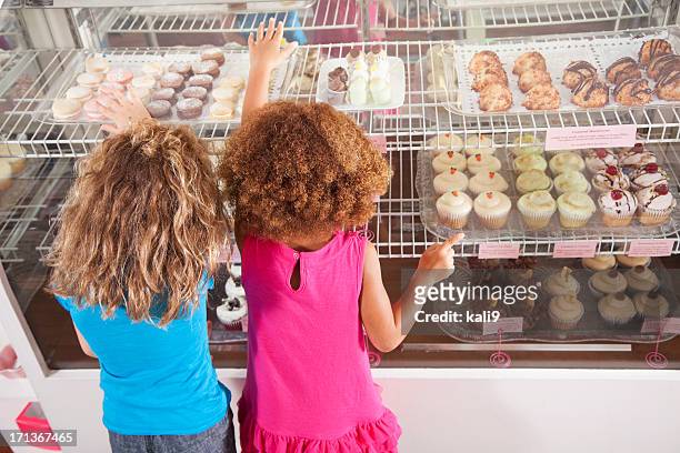 zwei mädchen in der bäckerei - cupcakes girls stock-fotos und bilder