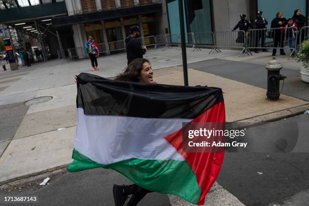 Person runs with the Palestinian flag as people protest in support of the people of Palestine near the Israeli consulate on October 8, 2023 in New...