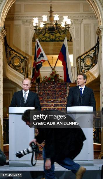 Photographer passes in front of the podiums with Britain's Prime Minister Tony Blair and Vladimir Putin, President of the Russian Federation, during...