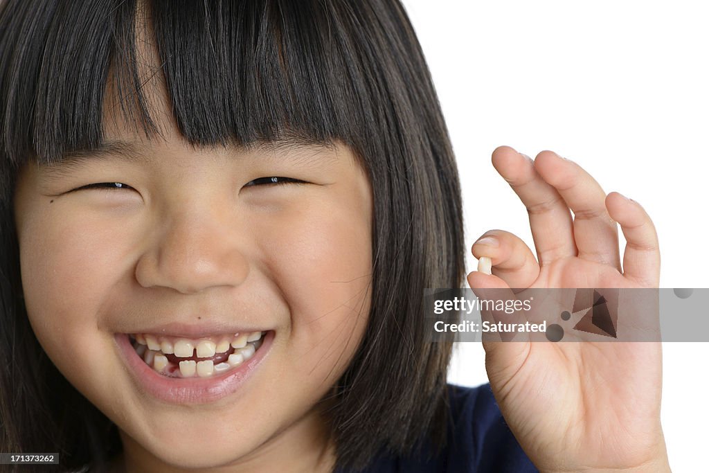 Smiling Girl Holding Missing Tooth