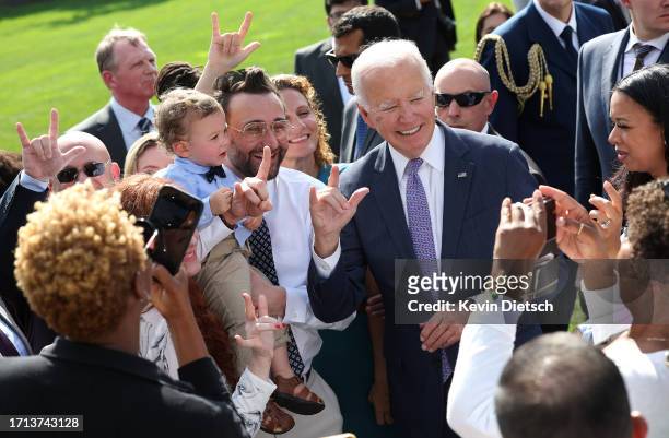 President Joe Biden signs "I love you," in American sign language as he greets advocates and members of the disabled community following an event...
