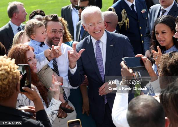 President Joe Biden signs "I love you," in American sign language as he greets advocates and members of the disabled community following an event...