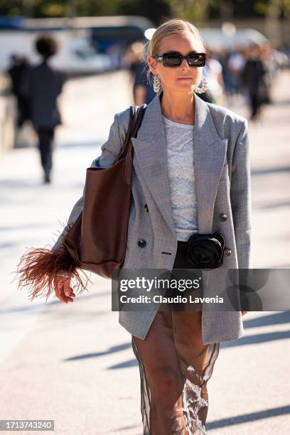 Guest wears a grey blazer, black sheer skirt, brown bag and black sunglasses, outside Balenciaga, during the Womenswear Spring/Summer 2024 as part of...