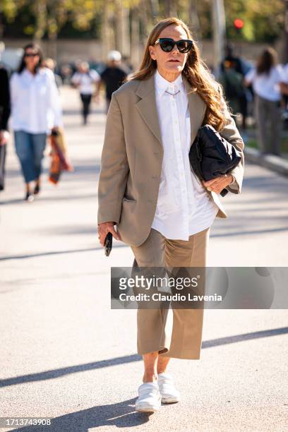 Guest wears a white shirt, beige suit, black bag and white shoes, outside Balenciaga, during the Womenswear Spring/Summer 2024 as part of Paris...
