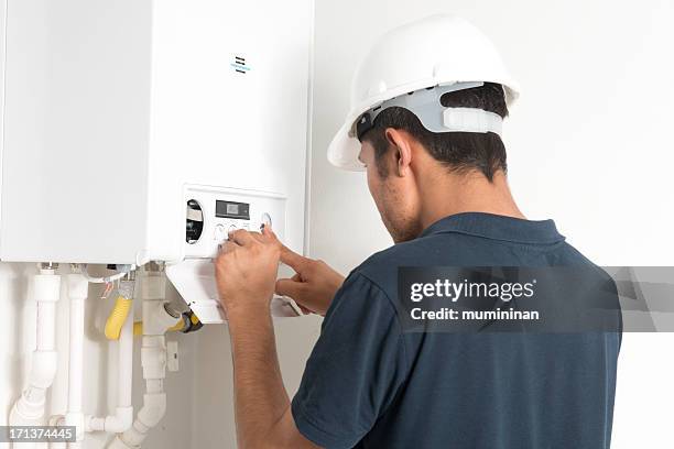 male technician working in a boiler in a white room - boilers stock pictures, royalty-free photos & images