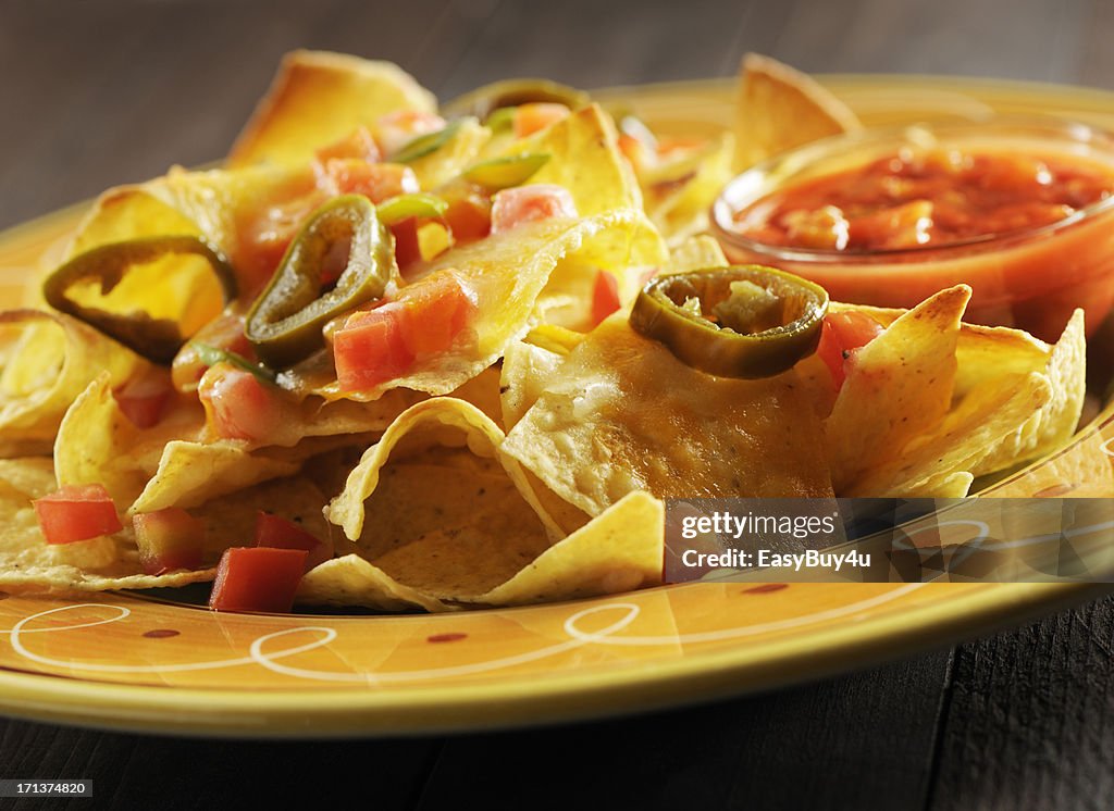 Close-up of a plate with nachos, olives, tomatoes and sauce