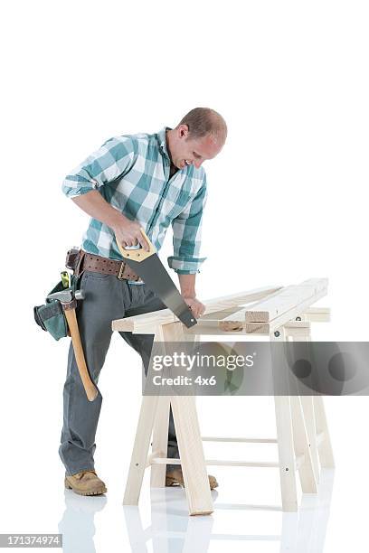 carpenter cutting wooden plank with a saw - sawhorse stock pictures, royalty-free photos & images