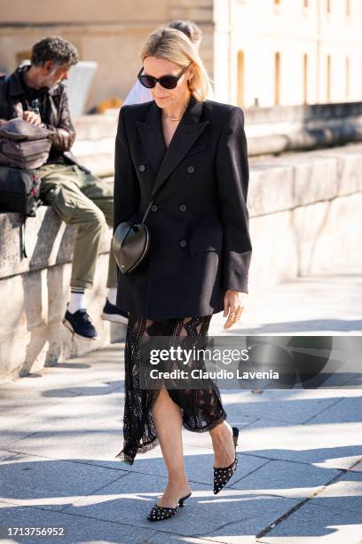 Guest wears a black blazer, black lace midi skirt, black kitten heels and black Alaia bag, outside Balenciaga, during the Womenswear Spring/Summer...