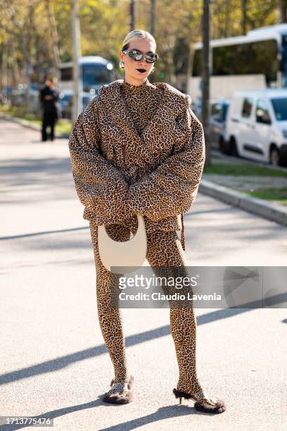 Guest wears a leopard priint top, pants and puffed jacket, Coperni beige bag and silver sunglasses, outside Balenciaga, during the Womenswear...
