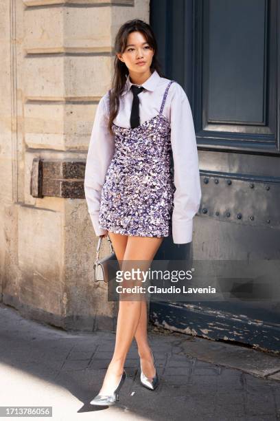 Lily Chee wears a white shirt with black tie, purple sequins mini dress and silver Valentino bag and heels, outside Valentino, during the Womenswear...