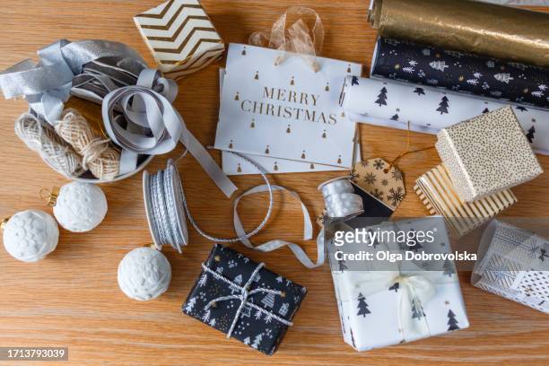 wrapped christmas presents, a wrapping paper, gift bags, ribbons and christmas baubles on a desk - gift bag stock pictures, royalty-free photos & images