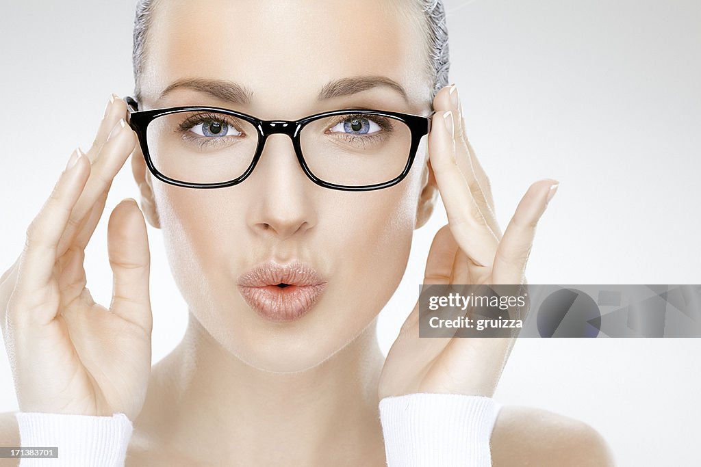 Beauty headshot of beautiful woman holding eyeglasses and blowing kisses