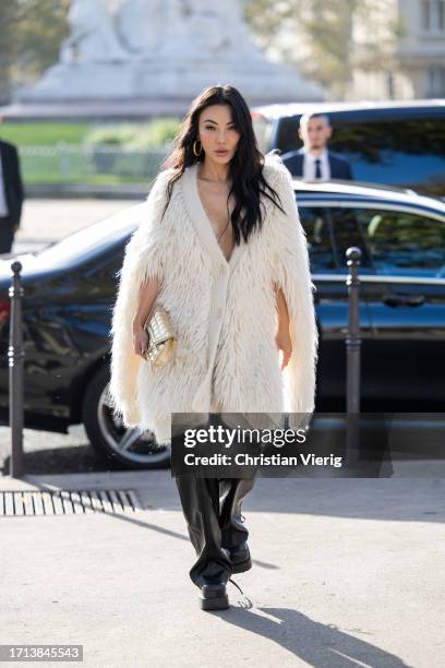 Jessica Wang wears white fur cape, golden bag, black leather pants outside Stella McCartney during the Womenswear Spring/Summer 2024 as part of Paris...