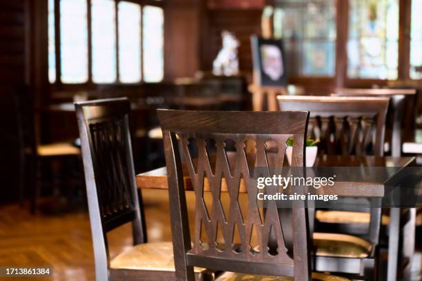 backrest of a wooden chair of a table inside an empty restaurant or cafeteria, rear view - vintage desktop wallpaper stock pictures, royalty-free photos & images