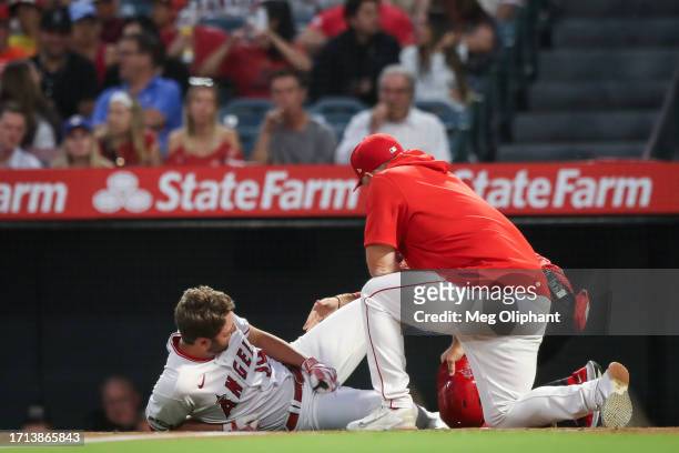 Nolan Schanuel of the Los Angeles Angels is injured and meets with manager Phil Nevin in the first inning against the Texas Rangers at Angel Stadium...