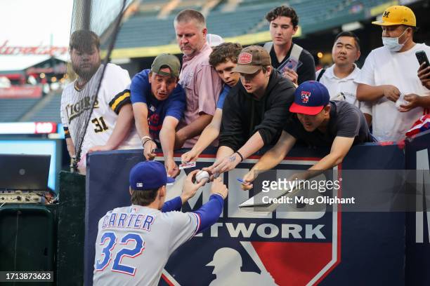 Evan Carter of the Texas Rangers signs autographs for fans before the game against the Los Angeles Angels at Angel Stadium of Anaheim on September...