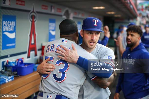 Mitch Garver of the Texas Rangers hugs Adolis Garcia in the dugout before the game against the Los Angeles Angels at Angel Stadium of Anaheim on...