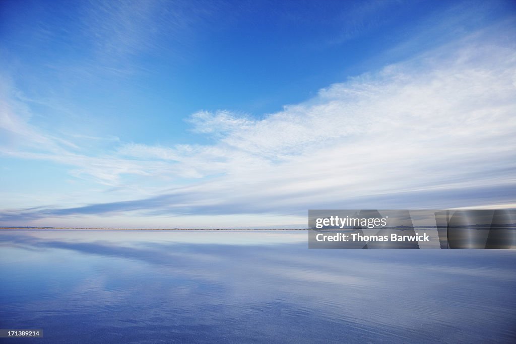Sky and clouds reflecting in calm lake at sunset