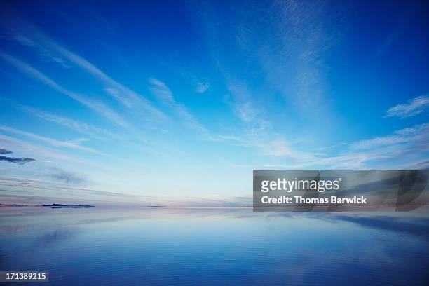 sky reflecting in calm lake at sunset - imponente fotografías e imágenes de stock