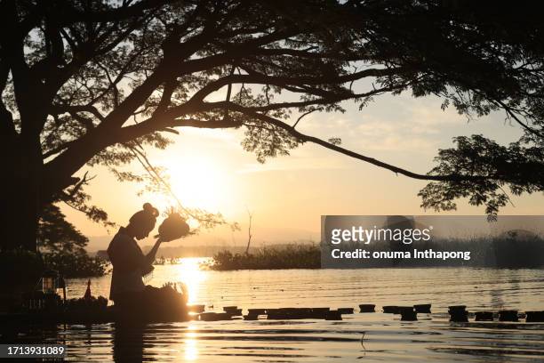 a beautiful asian woman floats a leaf basket called krathong in thai to pray respect to the goddess of water at the river on the full moon day of november - buddhist goddess stockfoto's en -beelden