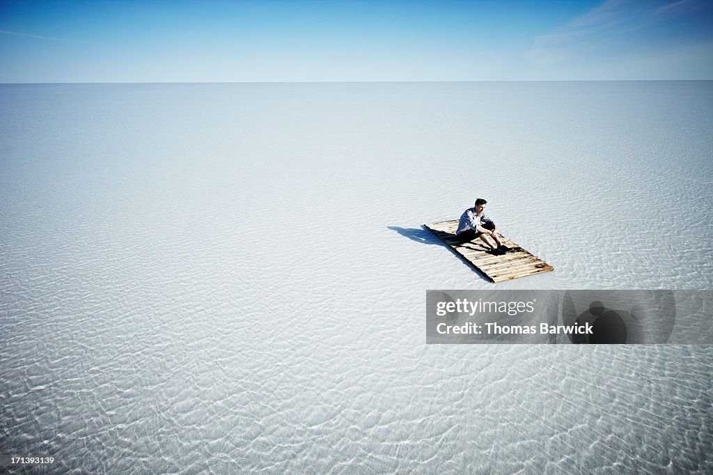 Businessman sitting alone on life raft