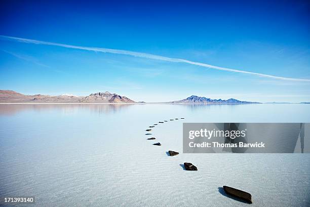 curved path of stones in calm lake - maxim barron stock pictures, royalty-free photos & images