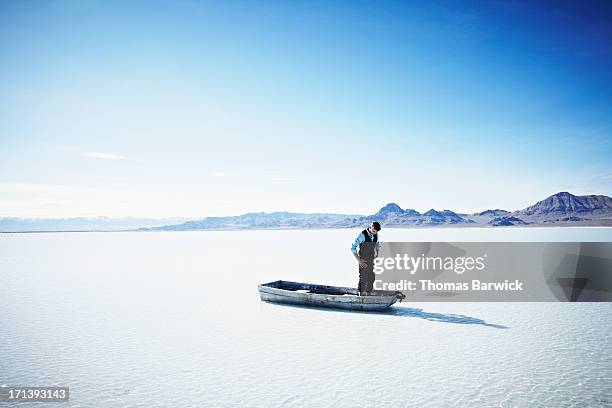 businessman in small boat on lake looking down - abandoned business stock pictures, royalty-free photos & images