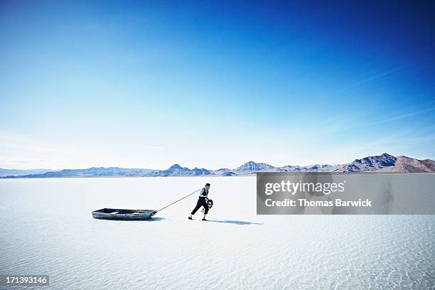 businessman pulling small boat in shallow water - fast forward bildbanksfoton och bilder