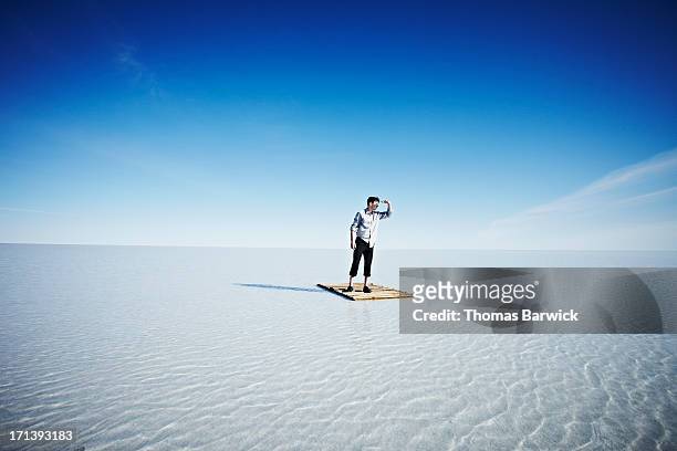 businessman standing alone on life raft - the castaway ストックフォトと画像