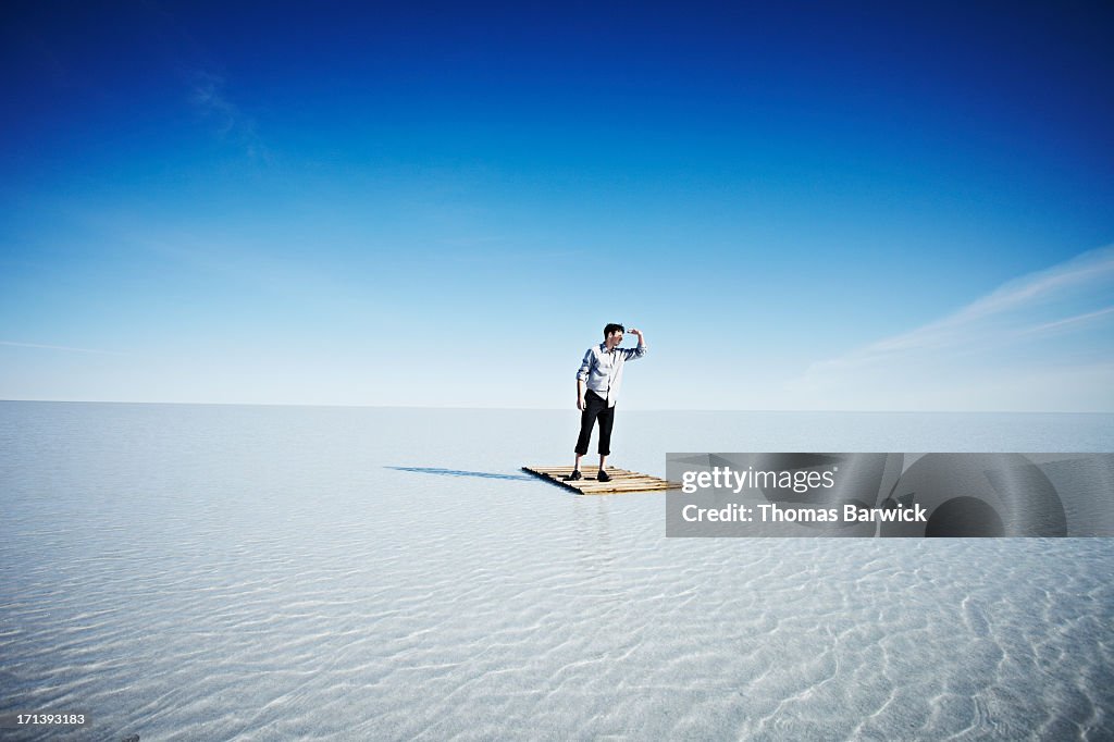 Businessman standing alone on life raft